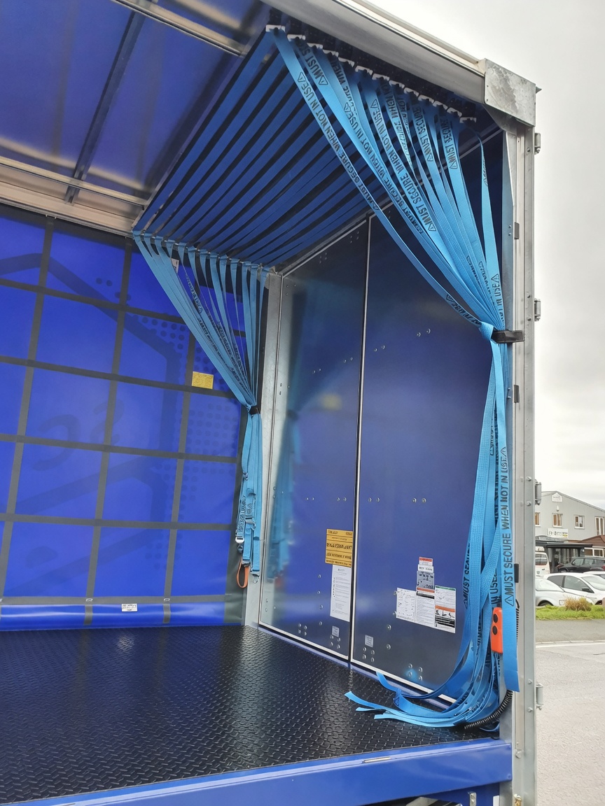 New empty curtain-sided body with hanging webbing straps gathered at the rear